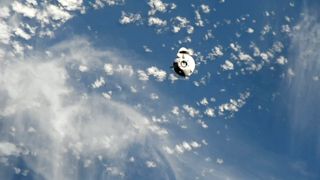 a white space capsule is seen with earth in the background