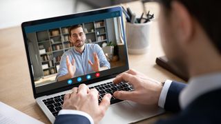 Two professionally dressed men talking to each other using a webcam on a virtual call.