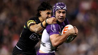 Jahrome Hughes (R), wearing white and purple kit and scrum cap, is tackled by Casey McLean (L), wearing black, in Panthers vs Storm NRL.