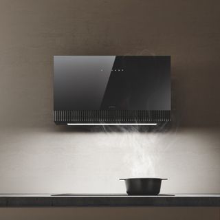 A black pot sitting under a black high tech extractor hood