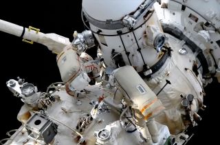 Russian cosmonauts Sergey Prokopyev and Dmitry Petelin work to connect cables to a newly relocated equipment airlock from the Nauka multipurpose laboratory module during a May 3, 2023 spacewalk outside of the International Space Station.