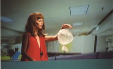 Photograph of woman holding balloon-like bag, a still from the exhibition ‘Miranda July: New Society’ at Fondazione Prada, Milan