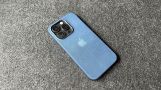 The iPhone 15 Pro with a Pacific Blue Apple FineWoven case on.