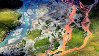 A bright orange river flowing next to a blue river