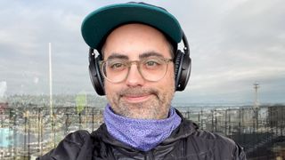 A man wearing a Patagonia neck gaiter with the Seattle skyline behind him.