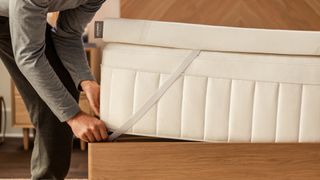 Best mattress topper: The image shows a man place a Tempur-Adapt mattress topper on his mattress