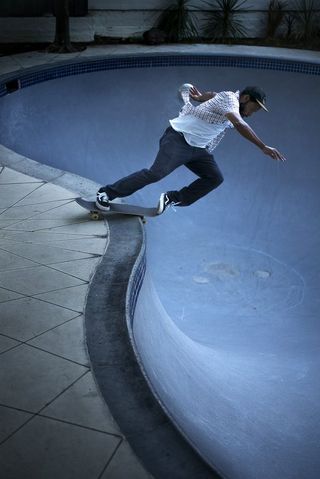 photo of skateboarder Ray Barbee as he begins move in empty swimming pool