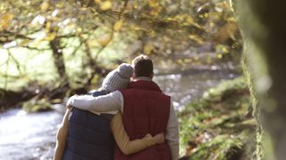 man and woman comforting each other besides a river