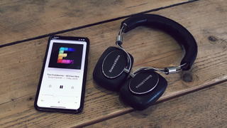 Bowers &amp; Wilkins headphones next to iPhone playing podcast