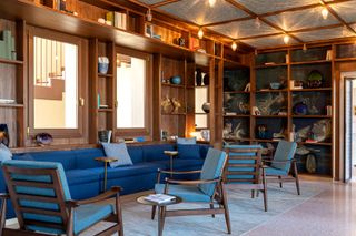 The reading room, with blue armchairs and walls lined with shelves