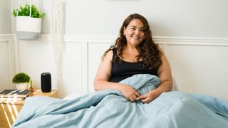 Attractive heavy woman sitting on a bed smiling at the camera