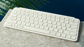 a white wireless bluetooth keyboard resting on a clean white table