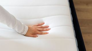 A woman&#039;s hand feels a memory foam mattress to check if it needs replacing