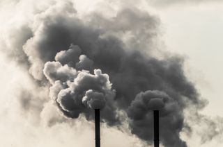 Factory smoke stacks releasing clouds of greenhouse gases.