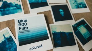 A box of Polaroid Blue 600 film surrounded by eight prints