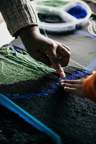 Two hands creating beaded fringes