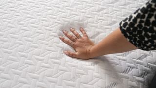 A hand presses into the Nectar Classic Memory Foam Mattress to test the temperature regulation and pressure relief