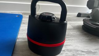 Image of Bowflex SelectTech 840 kettlebell on wooden floor next to workout mat during kettlebell workout