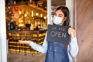 Masked server holding sign announcing a bar is open