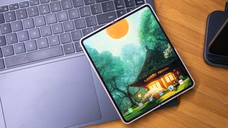 A Samsung Galaxy Z Fold 4 unfolded showing a Backdrops wallpaper on the homescreen, resting on the keyboard of a Galaxy Book 3 Ultra