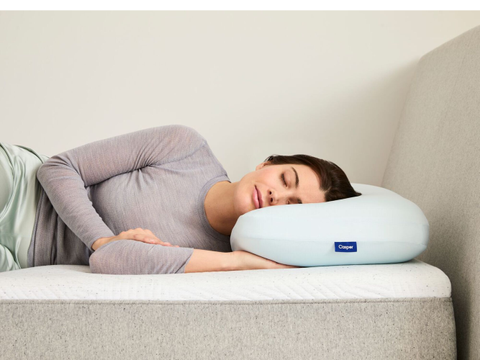 A woman lying on a Casper Hybrid Pillow with Snow Technology