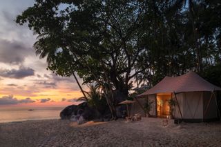 Aman cabana pop-up shop in a beach setting with a Thai-inspired roof