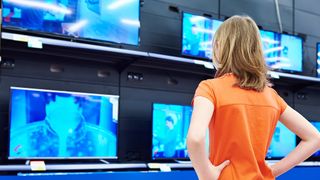 A teen stands in front of LCD TVs in a store