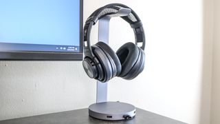 The Satechi Aluminum USB Headphone Stand on a desk with a pair of headphones hanging from it