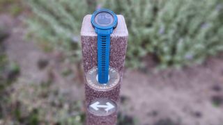 The Garmin Instinct 2 Solar sitting on a trail marker