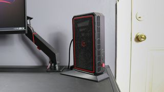 The Minisforum AtomMan G7 PT mini PC on a desk next to a monitor arm