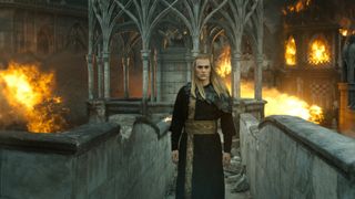 Annatar/Sauron (Charlie Vickers) stands on a bridge as flames erupt through town behind him in "The Lord of the Rings: The Rings of Power" season 2