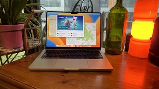 A 2023 14-inch MacBook Pro on a wooden counter, near a retro lamp.