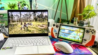 ROG Zephyrus (2024) gaming laptop in white playing Red Dead Redempiton 2, sitting on a table next to a Steam Deck OLED in a white case.