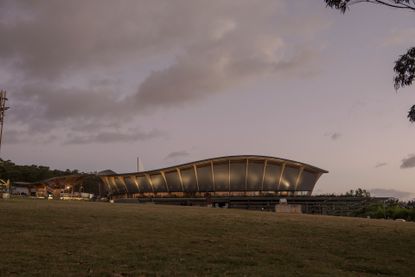 The MACA building captured from afar with trees and the sky in the background photographed at dusk