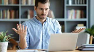 A man looking at his computer in disbelief due to internet issues