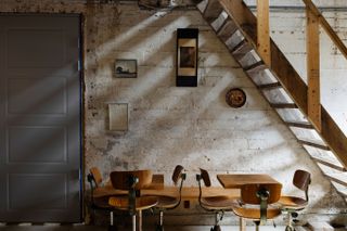 Tables and chairs beneath open stairway against industrial-looking wall at Trevarefabrikken hotel Norway