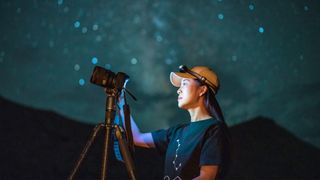woman photographing the night sky with one of the best astrophotography cameras