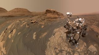 a rover on the surface of mars with a bunch of rocks and mountains surrounding