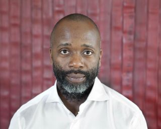 Artist Theaster Gates photographed in front of a work from his Civil Tapestry series