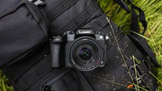 Bästa 4K-kamera: En svart Lumix-kamera ligger utomhus på en svart kameraväska som ligger på en gräsmatta utomhus.