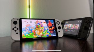 En Switch & en Switch OLED står uppställda på ett bord bredvid varandra.