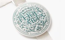 Close-up of the paper Terra Carta Seal by LoveFrom, with green embossed type on white paper