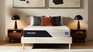 The Nectar Classic Memory Foam Mattress in a box placed on a white bedframe and bookended by large black dome bedside lamps