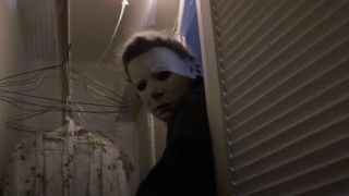 Michael Myers pokes his head through the coat closet in Halloween