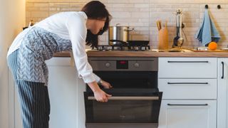 A woman leaning over to open an oven