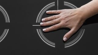 A hand touching the burner of an induction cooktop to show it's cool