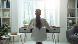 A woman sitting at a desk in front of a large window