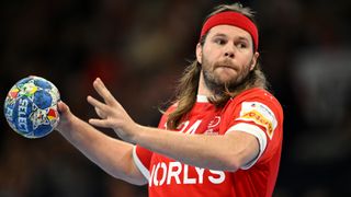 Mikkel Hansen, in close-up, about to shoot in handball, wearing the Denmark red shirt, ahead of the 2024 Olympic Games. 