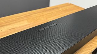 Samsung HW-Q990D soundbar system detail shot showing controls on top of bar