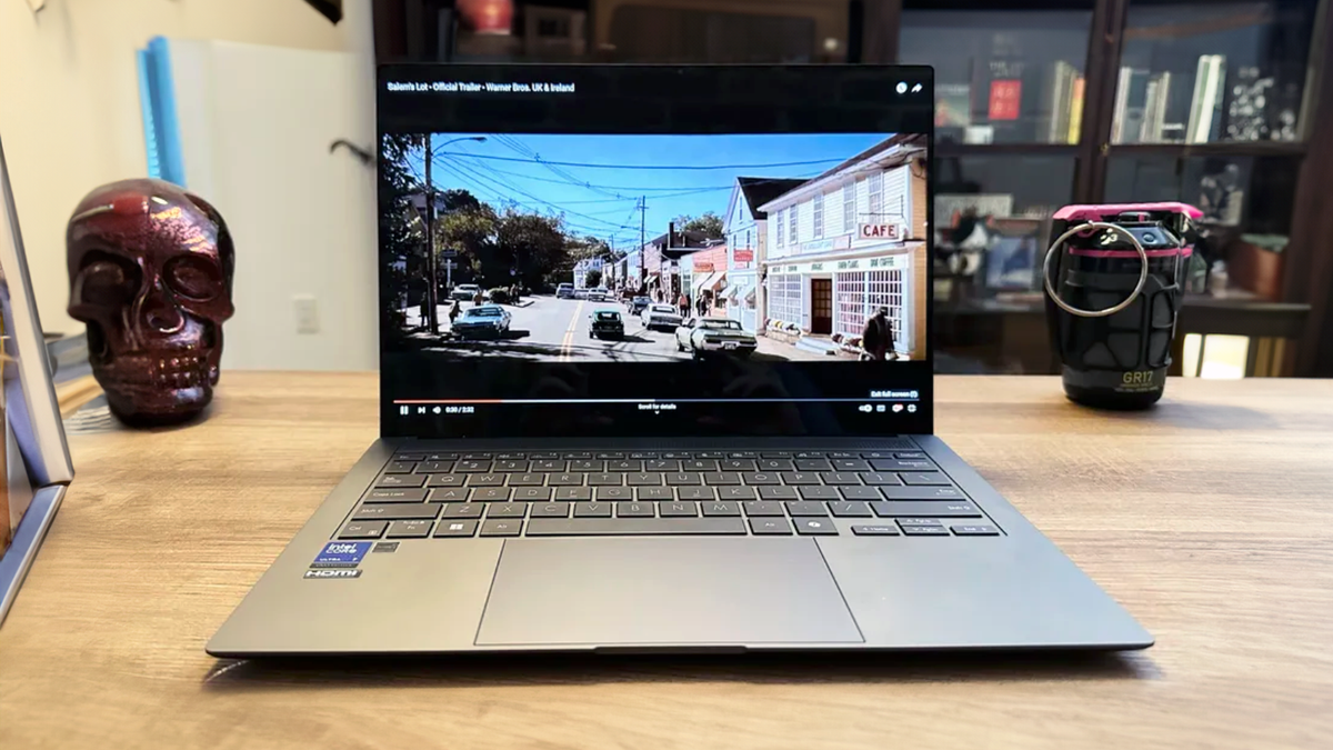 An Asus Zenbook S 14 sitting on a wooden desk.